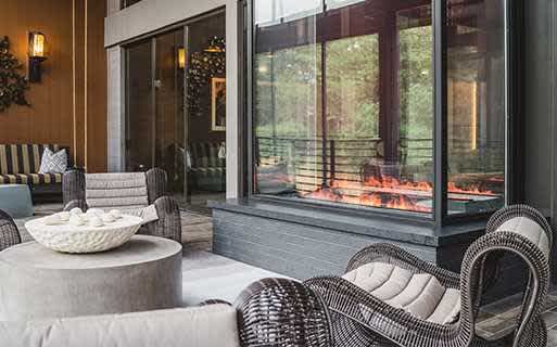 A modern patio with a fireplace and comfortable seating.