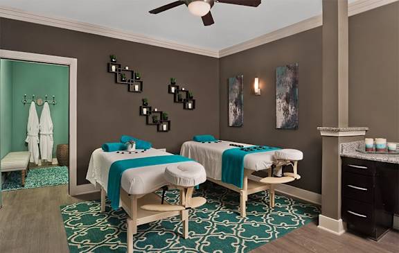 A spa room with two massage tables and a green patterned rug.