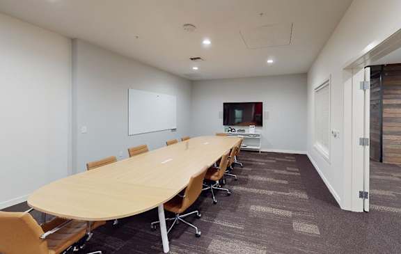 A conference room with a long table and chairs.
