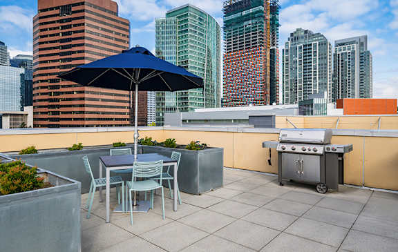 A table with chairs and an umbrella on a rooftop patio.