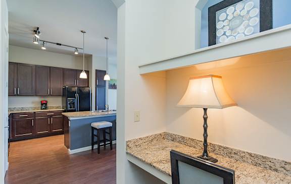 A kitchen with a bar stool and a table with a lamp on it.