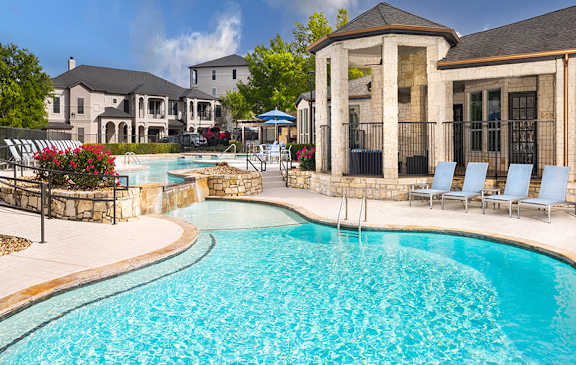 A large swimming pool with a stone building in the background.