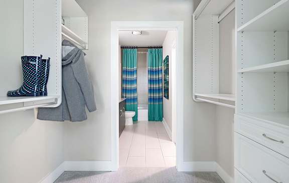 A hallway with a coat hanging on the wall and a pair of boots on the shelf.