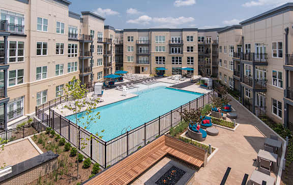 A large swimming pool surrounded by a black fence and a wooden deck.