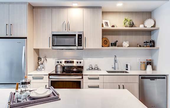 A modern kitchen with a refrigerator, microwave, oven, and sink.
