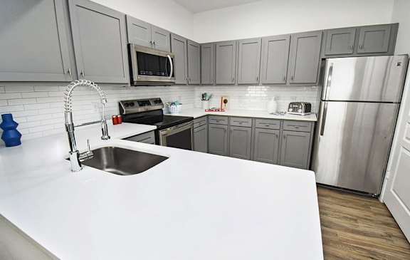A modern kitchen with a white countertop and stainless steel appliances.