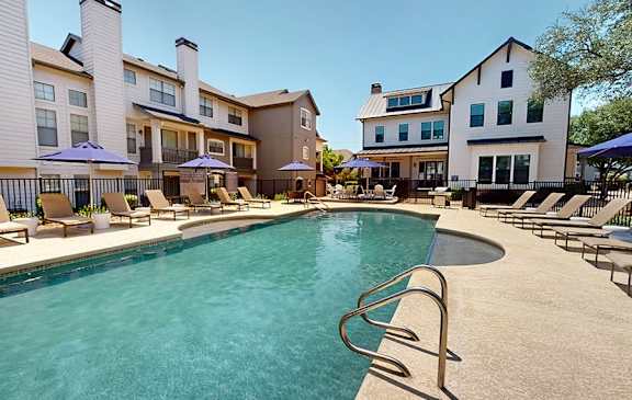 A swimming pool surrounded by lounge chairs and umbrellas.