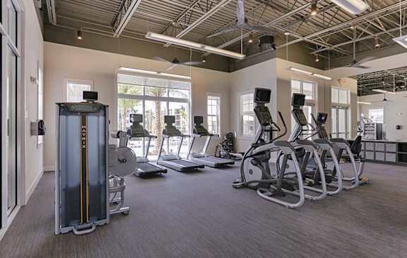 A gym with treadmills, elliptical machines, and a weight stack.