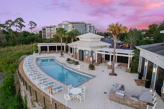 A large outdoor pool area with lounge chairs and a building in the background.