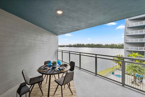 A balcony with a table and chairs overlooking a pool.