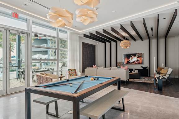 A pool table is in the middle of a room with a bench and a chair.
