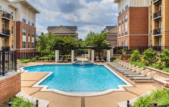 A large swimming pool surrounded by lounge chairs and buildings.