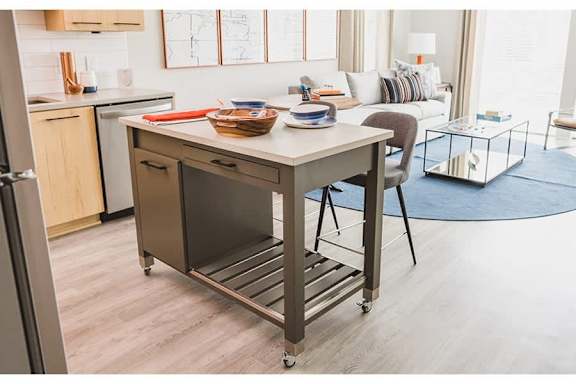 A kitchen island with a chair and a basket on top.