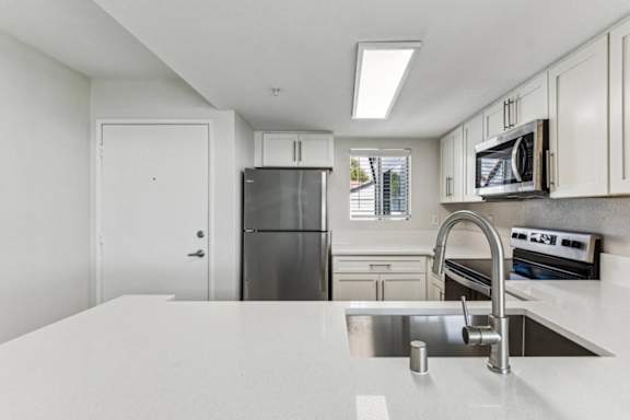 A kitchen with a white counter top and stainless steel appliances.