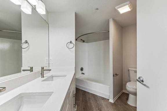 A white bathroom with a sink, mirror, toilet, and bathtub.