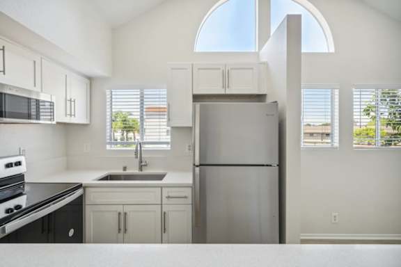 A kitchen with a refrigerator, sink, and stove.