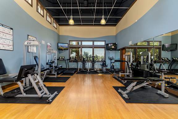 a gym with cardio machines and weights on a wood floor