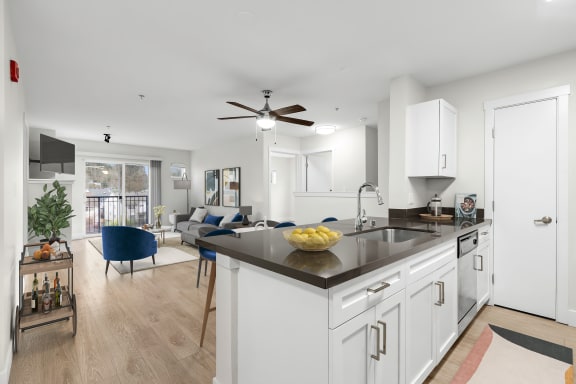 a kitchen and living room with white walls and wood flooring