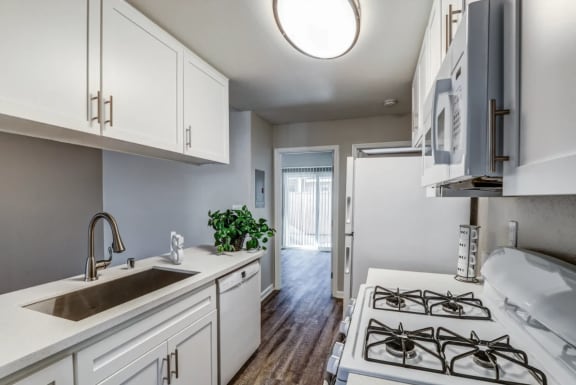 an empty kitchen with white cabinets and a sink and a stove at Aspire Seneca, Victorville