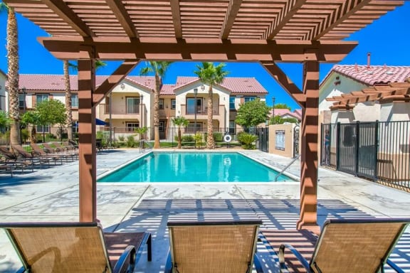 a swimming pool with chairs and a pergola at Riverton of the High Desert Apartments, Victorville, CA