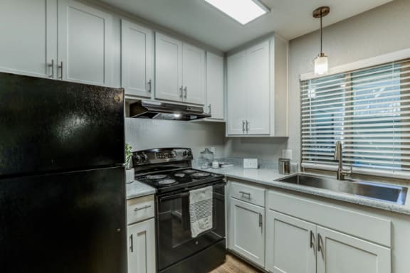 a kitchen with black appliances and white cabinets  at Aspire Upland Apartments, Upland, California