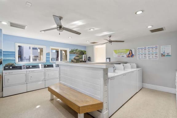 a laundry room with washing machines and a bench at Aspire Rialto, Rialto, CA, 92376