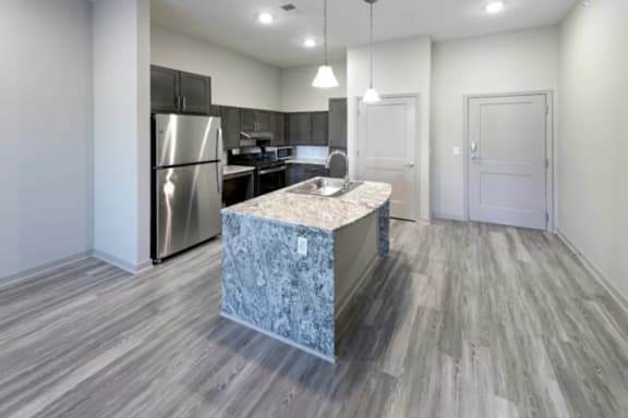 A kitchen with a marble island and stainless steel appliances at Woodstone at Metro North Crossing Apartments, Kansas City, MO