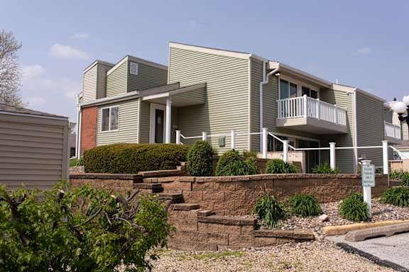 A building with a green and grey exterior and a balcony.