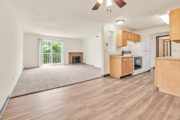 A living room with a fireplace and a kitchen area in the background. at Winding Hills Apartments, Davenport, 52807