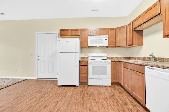 A kitchen with white appliances and wooden cabinets. at Deer Valley Apartments, Silvis, Illinois