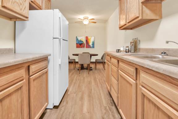 A kitchen with wooden cabinets and a white refrigerator. at Indian Ridge Apartments, Iowa, 52807