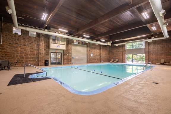 A large indoor swimming pool with a wooden ceiling and brick walls. at Kimberly Club Apartments, Davenport, 52807