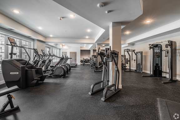 A spacious gym with a variety of equipment including treadmills, elliptical machines, and weight machines.