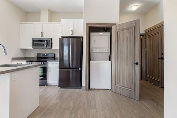 A kitchen with a black refrigerator, white dishwasher, and a black stove top.