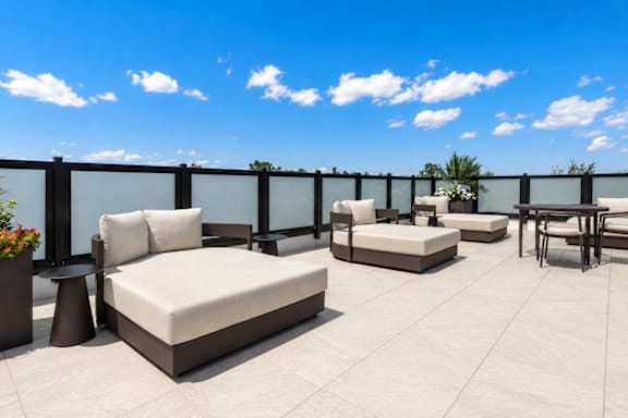 A patio with white furniture and a black railing.