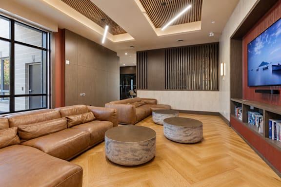 A living room with a large leather couch and a television on the wall.