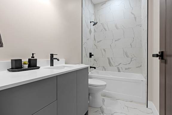 A white toilet sits in a bathroom with a marble wall.