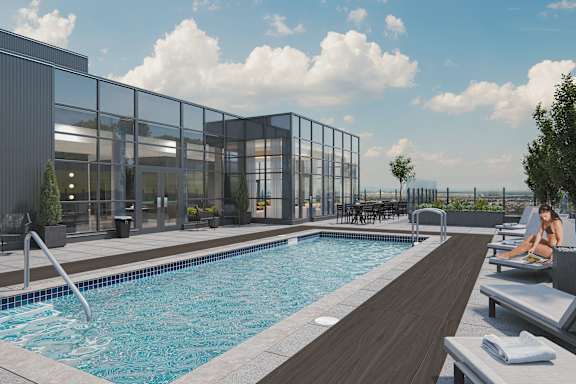 A woman is sitting by a pool on a sunny day.