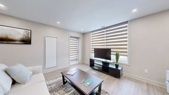 A living room with a white couch, a wooden coffee table, and a television.