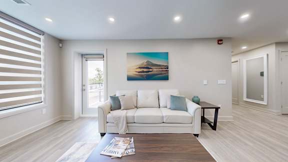 A living room with a couch, a coffee table, and a painting on the wall.