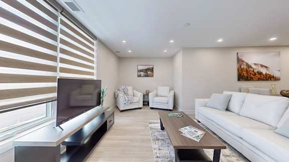 A modern living room with a television, white sofa, and a coffee table.