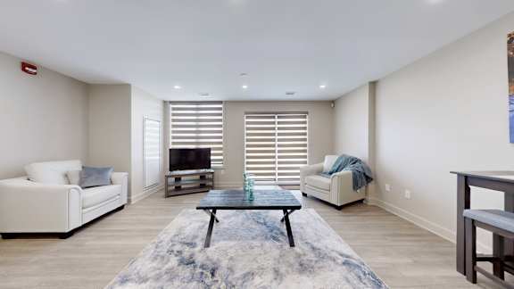 A living room with a white couch, a coffee table, and a television.