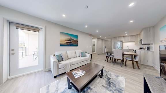 A modern living room with a white sofa and a painting on the wall.