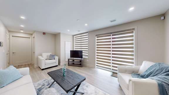 A modern living room with a white sofa, a black coffee table, and a television.