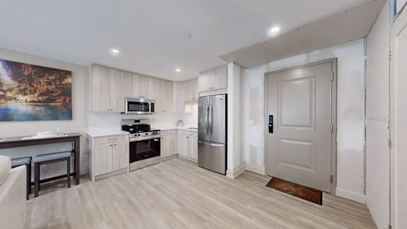 A kitchen with a refrigerator, oven, and sink.