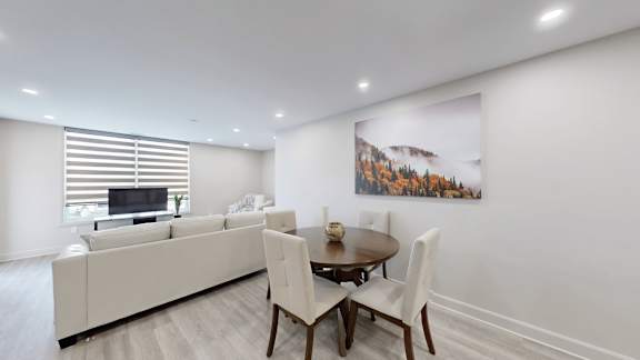 A living room with a white couch, a wooden table, and a painting on the wall.