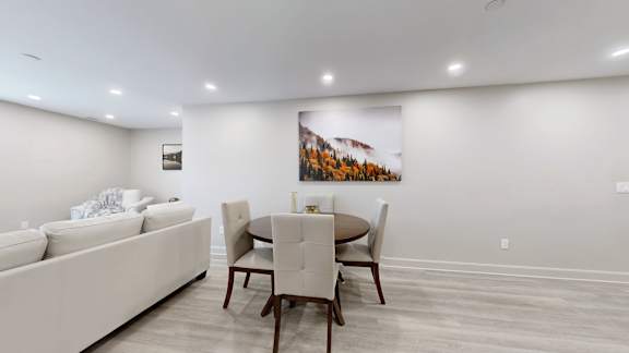 A white couch sits in a living room with a wooden table and chairs.