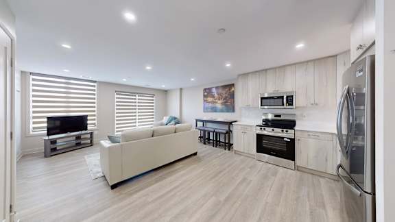 A modern kitchen with a white couch and wooden cabinets.
