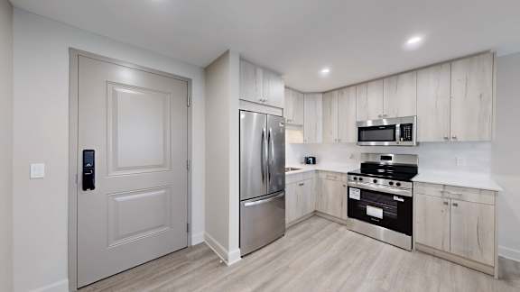 A kitchen with a refrigerator, oven, and microwave.