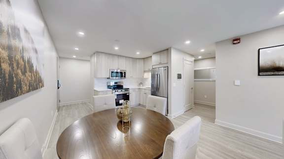 A modern kitchen with a wooden table and white chairs.